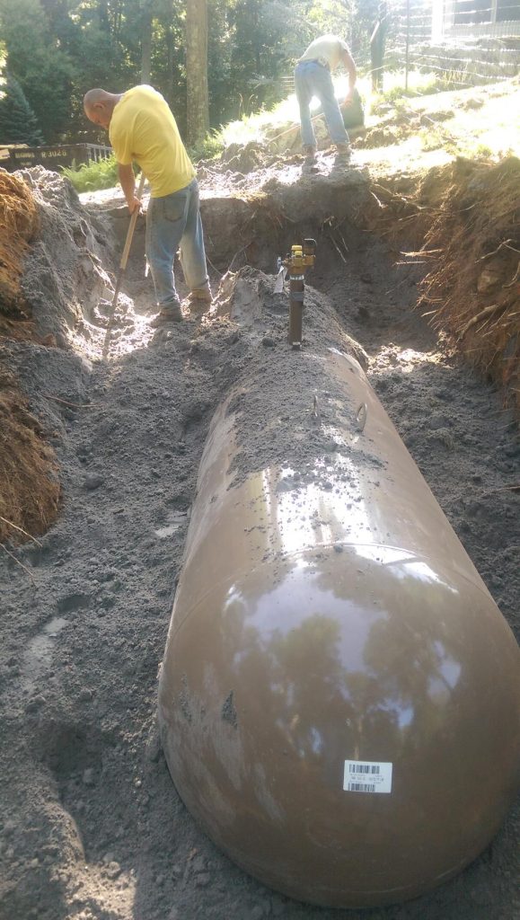 Workers installing underground tank in trench