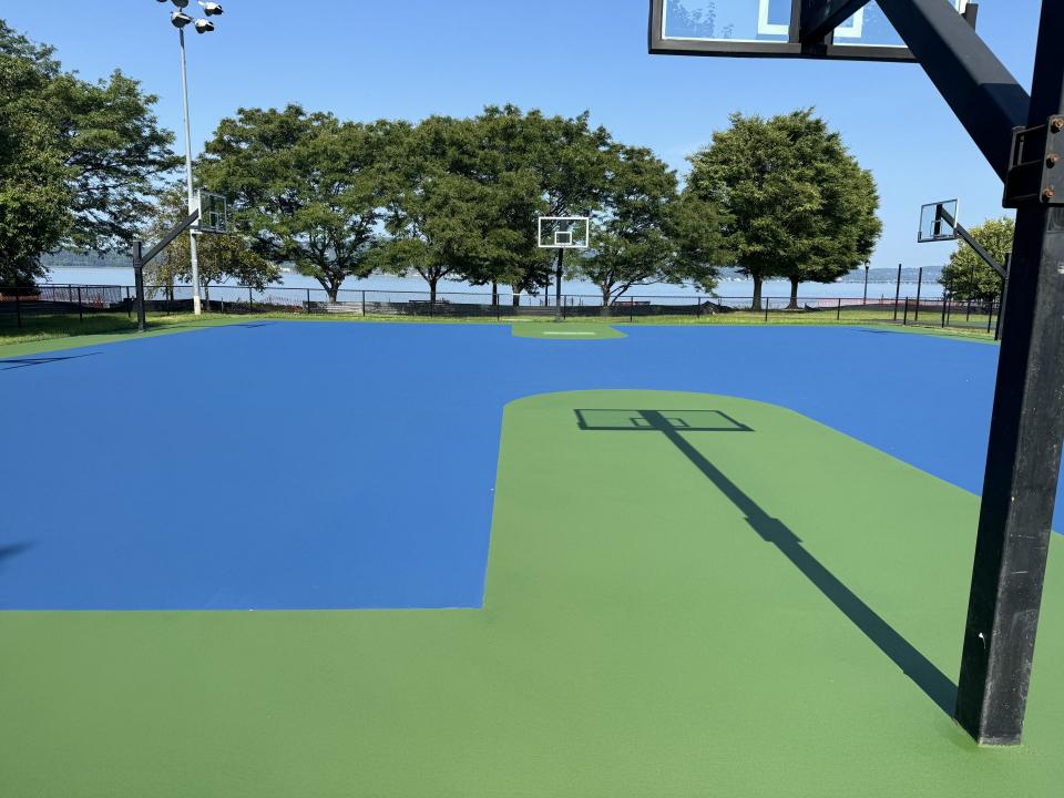 Outdoor basketball court with blue-green surface.