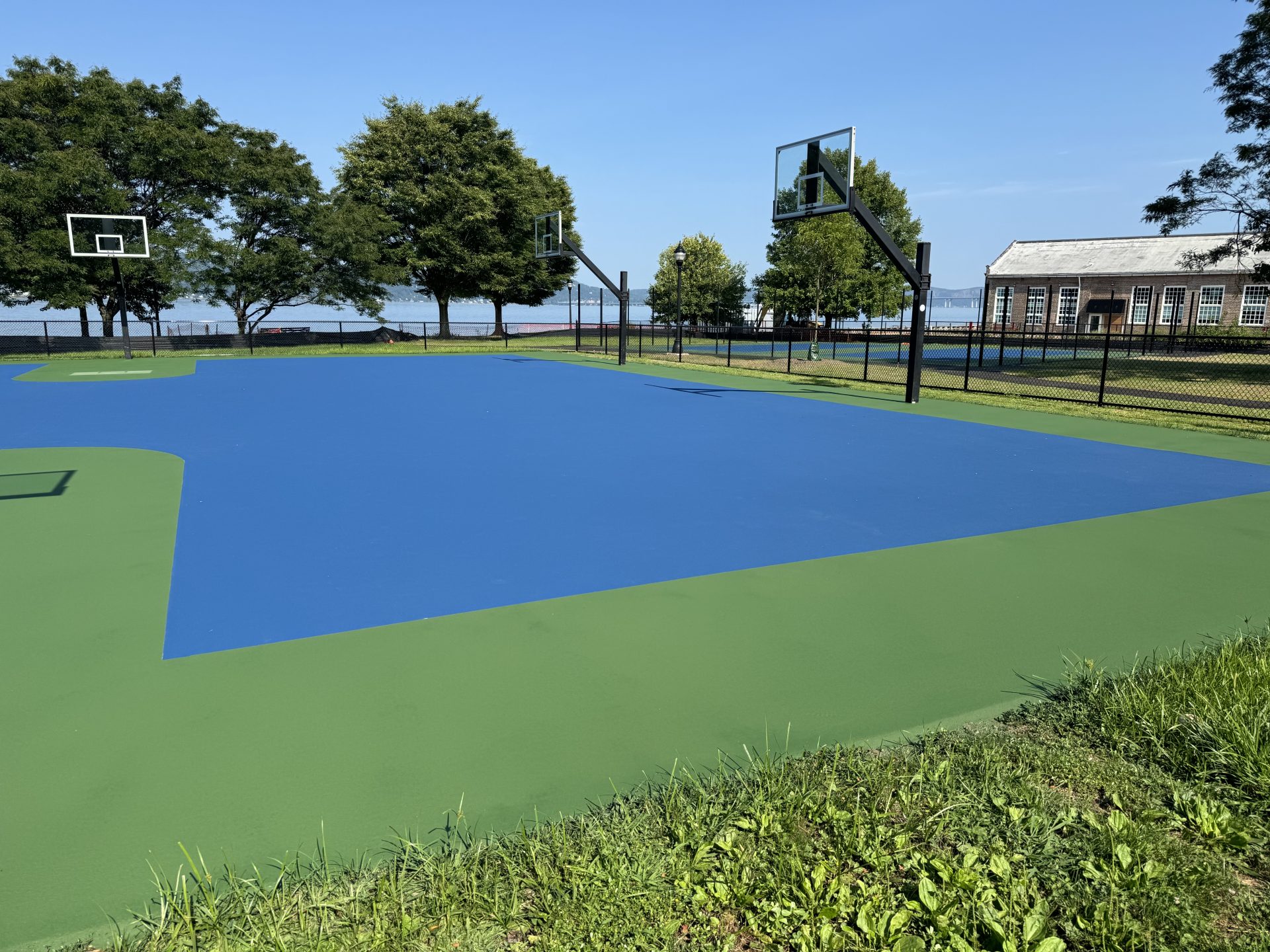 Outdoor basketball court with fresh blue surface.